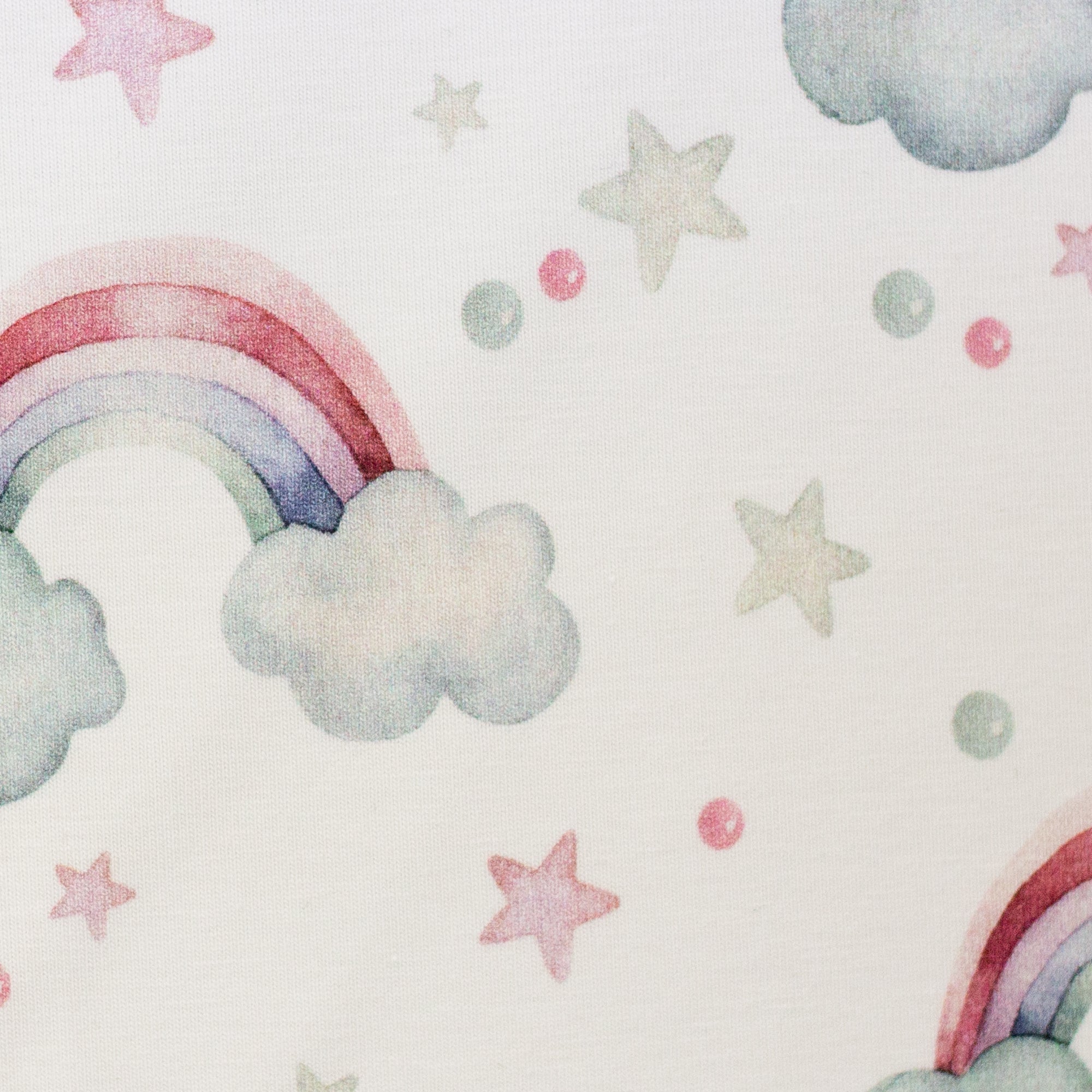 Zu sehen ist eine Nahaufnahme eines weichen, elastischen Baumwolljersey-Stoffs in weiß mit Regenbogen-Motiven, der durch seine angenehme, glatte Oberfläche ideal für Kleidung, Accessoires und kreative DIY-Projekte geeignet ist.