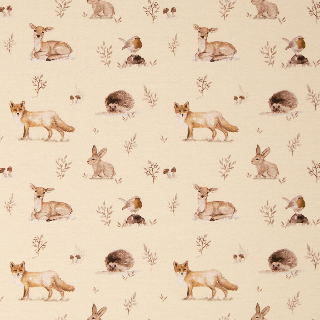 Zu sehen ist ein weicher, elastischer Baumwolljersey-Stoff in beige mit Motiven von Waldtieren wie Reh, Fuchs und Hase, der durch seine angenehme, glatte Oberfläche ideal für Kleidung, Accessoires und kreative DIY-Projekte geeignet ist.