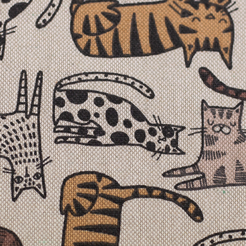 Zu sehen ist eine Nahaufnahme eines robusten Baumwoll-Canvas-Stoffs in warmen Natur-, Braun- und Beigetönen mit einem verspielten Katzenmotiv, der durch seine feste und griffige Oberfläche ideal für Taschen, Deko und kreative DIY-Projekte geeignet ist.