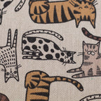 Zu sehen ist eine Nahaufnahme eines robusten Baumwoll-Canvas-Stoffs in warmen Natur-, Braun- und Beigetönen mit einem verspielten Katzenmotiv, der durch seine feste und griffige Oberfläche ideal für Taschen, Deko und kreative DIY-Projekte geeignet ist.