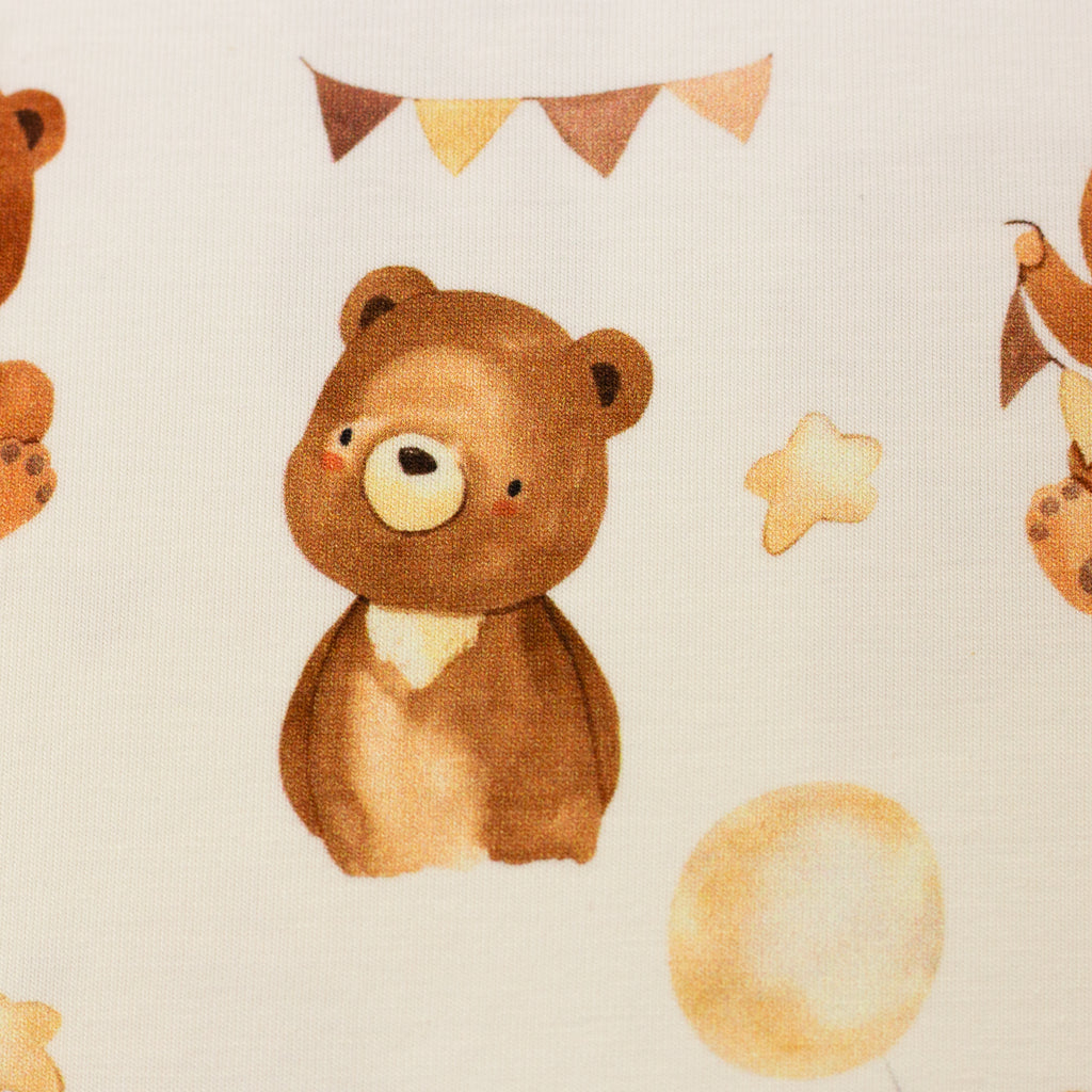 Zu sehen ist eine Nahaufnahme eines weichen, elastischen Baumwolljersey-Stoffs in cream mit süßen Bärchen, der durch seine angenehme, glatte Oberfläche ideal für Kleidung, Accessoires und kreative DIY-Projekte geeignet ist.