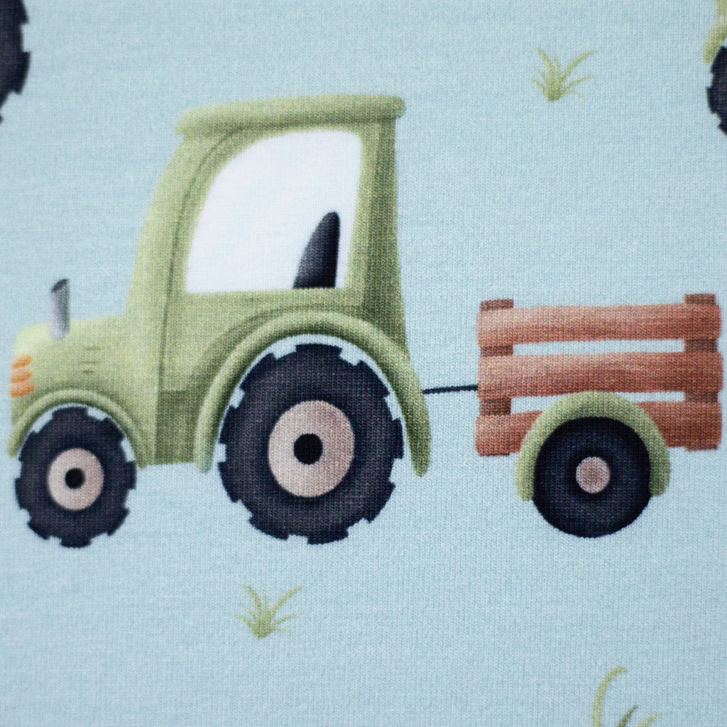 Zu sehen ist eine Nahaufnahme eines weichen, elastischen Baumwolljersey-Stoffs in blau mit einem kindgerechten Muster aus Trucks, LKWs und weiteren Fahrzeugmotiven, der durch seine glatte und dehnbare Oberfläche ideal für Kleidung, Accessoires und kreative DIY-Projekte geeignet ist.