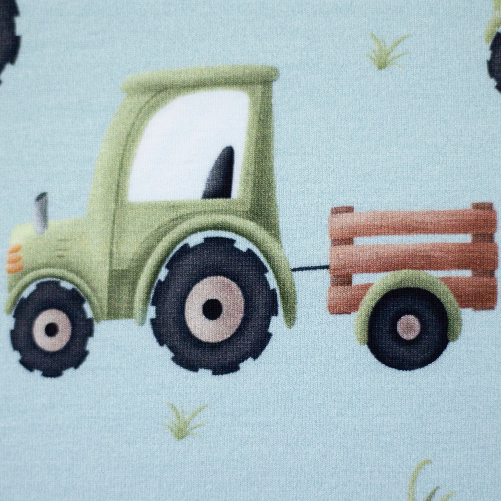 Zu sehen ist eine Nahaufnahme eines weichen, elastischen Baumwolljersey-Stoffs in blau mit einem kindgerechten Muster aus Trucks, LKWs und weiteren Fahrzeugmotiven, der durch seine glatte und dehnbare Oberfläche ideal für Kleidung, Accessoires und kreative DIY-Projekte geeignet ist.