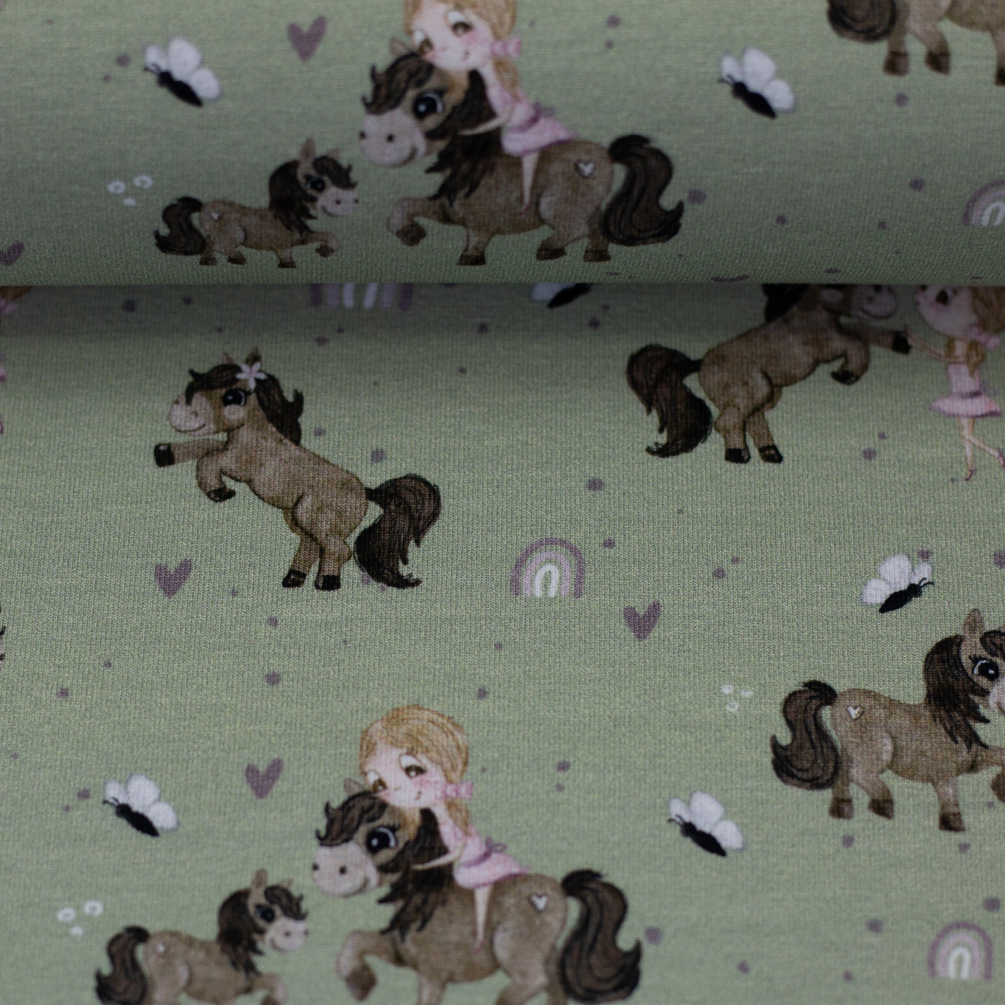 Zu sehen ist eine Nahaufnahme eines grünen Baumwolljerseys mit Pony- und Naturmotiven, elastisch, geeignet für Kinderkleidung und Accessoires.