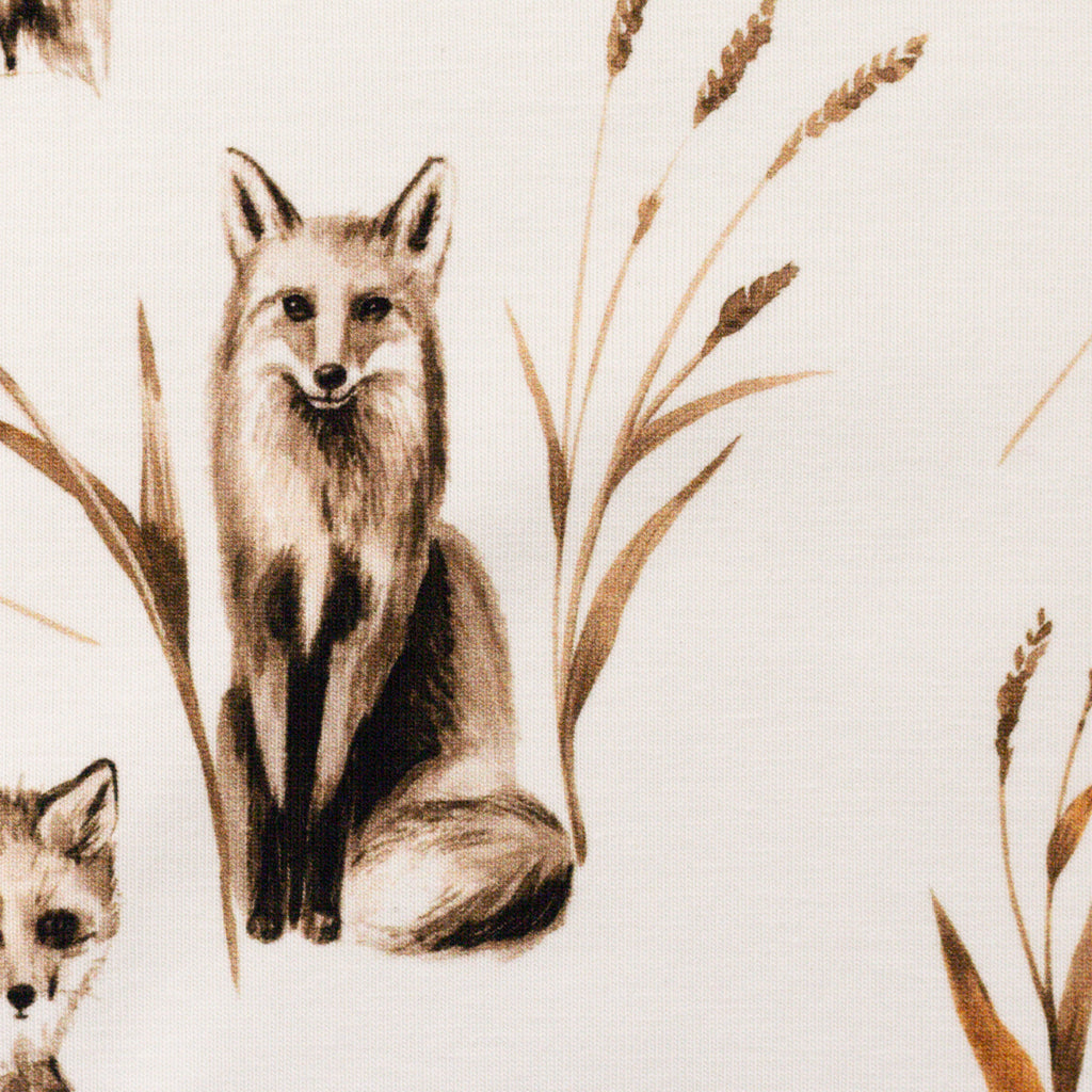 Zu sehen ist eine Nahaufnahme von weißem Baumwolljersey mit Fuchs- und Waldmotiven, elastisch und ideal für Kinderkleidung und DIY-Nähprojekte.