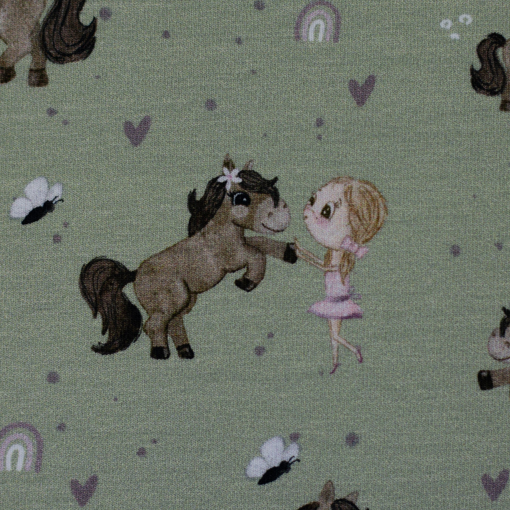 Zu sehen ist eine Nahaufnahme eines grünen Baumwolljerseys mit Pony- und Naturmotiven, elastisch, geeignet für Kinderkleidung und Accessoires.
