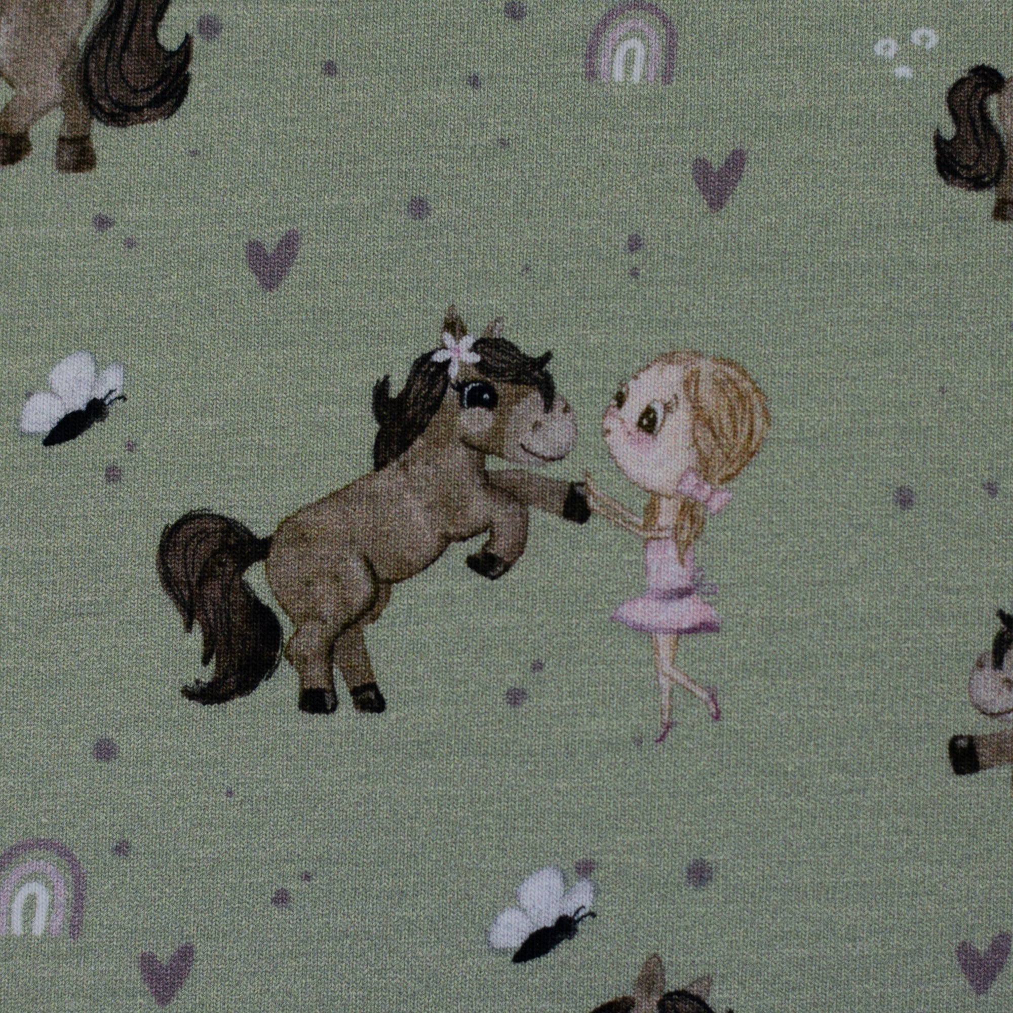 Zu sehen ist eine Nahaufnahme eines grünen Baumwolljerseys mit Pony- und Naturmotiven, elastisch, geeignet für Kinderkleidung und Accessoires.