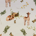 Zu sehen ist eine Nahaufnahme von weißem Baumwolljersey mit Reh- und Waldmotiven, elastisch und ideal für Kinderkleidung und DIY-Nähprojekte.