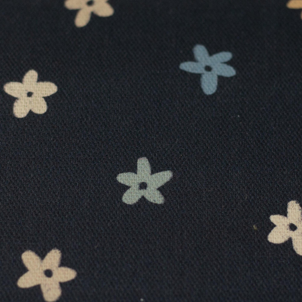 Zu sehen ist eine Nahaufnahme eines hochwertigen Deko-Baumwollstoffs in dunkelblau mit einem detailreichen, farbenfrohen Blumenmuster, der durch seine angenehme Haptik und stabile Webart ideal für kreative Näh- und Deko-Projekte geeignet ist.