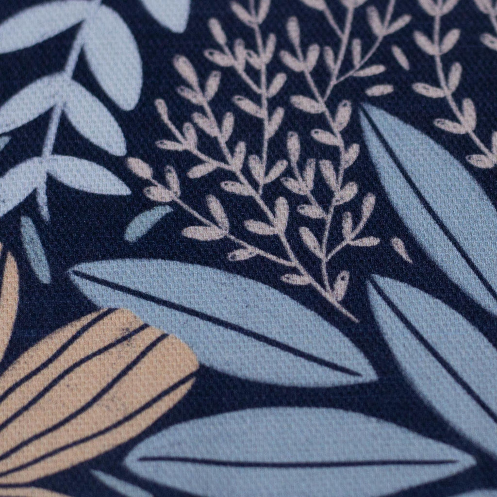 Nahaufnahme eines blauen Canvas-Stoffs mit floralem Blumenmuster, lebendigen Farben und detailreicher Baumwollstruktur.