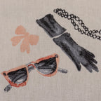 Nahaufnahme eines Canvas-Stoffs mit Paris-Fashion-Motiven, eleganten Damen, Eiffelturm, Parfum und Mode-Illustrationen.